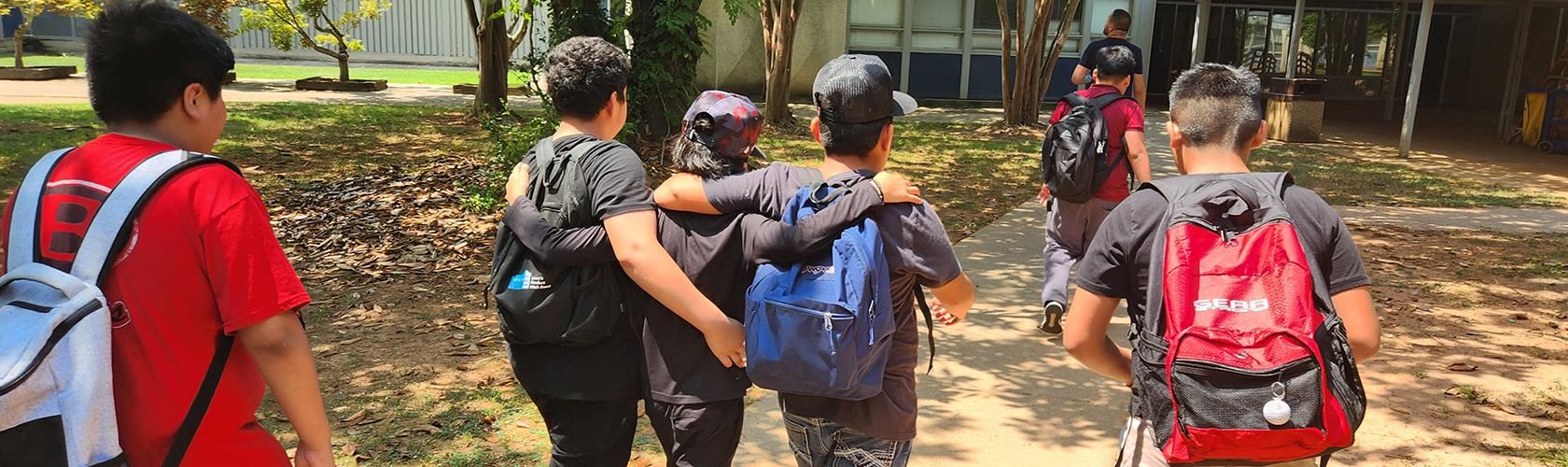 students walking into the school building together with arms around each other's shoulders